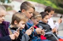 kids in a row are playing with phones -- The Legislature sent the bill to DeSantis last week, creating a Friday deadline for the governor to sign the bill, veto it or let it become law without his signature.