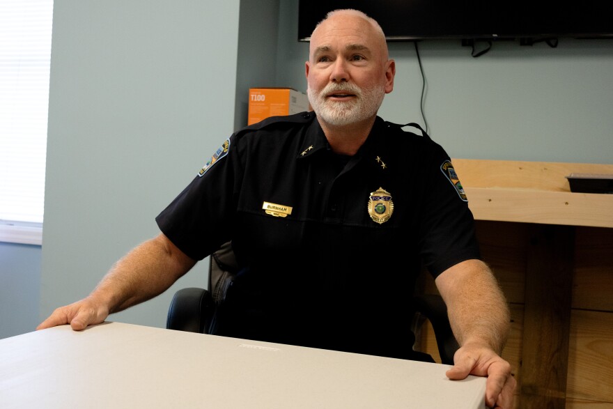 A man in a blue police uniform sits at a table.