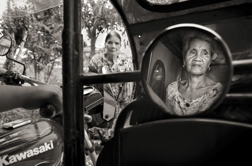 Isabelita Vinuya, 88, reflected in mirror, bids farewell to Perla Bulaon Balingit in the village of Mapaniqui in Pampanga. They are two of the last living "comfort women" of the Philippines. On Nov. 23, 1944, Vinuya, Balingit and some 100 other girls and women were taken to the Red House and systematically raped by the Japanese Imperial Army.