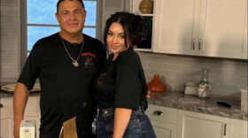 Frank and Alyssa Cappello are posing for a photo in front of a kitchen table. 