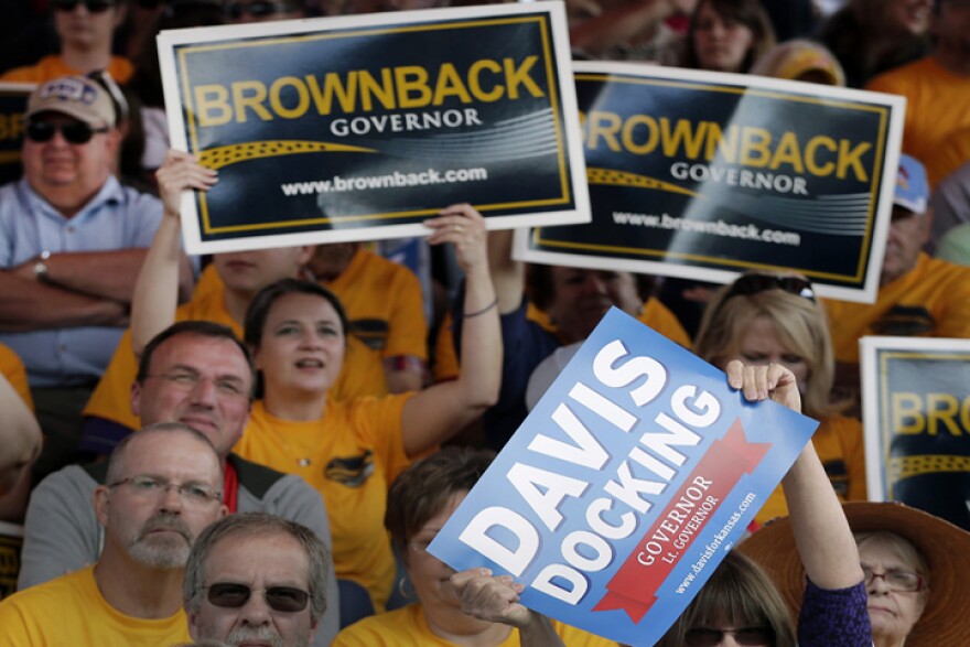 Volunteers with campaign signs during a debate between Sam Brownback and Paul Davis, at the Kansas State Fair in 2014. (Image credit: AP)