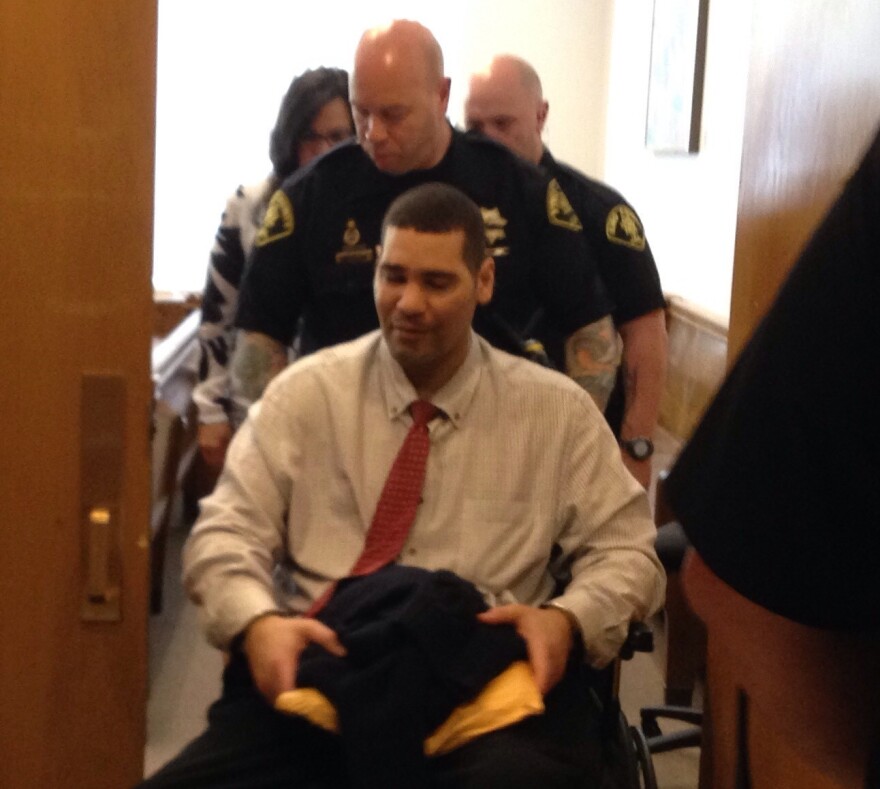 Guards wheel Monfort from the courtroom on Wednesday. Monfort is paralyzed from the waist down.