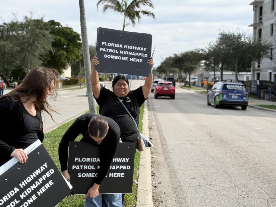 Protestors hold sign accusing Florida Highway Patrol of "kidnapping" community members in Lake Worth via immigration arrests.