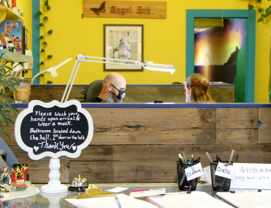 Chuck Miller gets a tattoo touched up by Shawna Holder at her shop Angel Ink Tattoo on Main Street in Oregon City, Ore., on March 1, 2022. Both looked forward to the end of Oregon&#39;s indoor mask mandate on March 12.