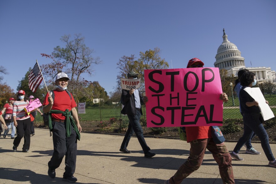 In this file photo, supporters of former President Donald Trump carry flags and signs as they parade past the Capitol in Washington, D.C. in November 2020. Over the last few years, county boards of election have seen high turnover. (AP Photo/J. Scott Applewhite)