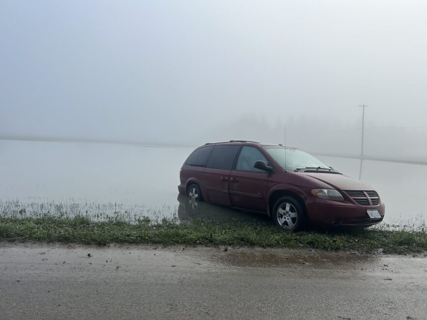 A minivan is stuck after flooding along Tualco Road near Monroe, Wash. on Saturday, Dec. 13, 2025. The Northwest is seeing warm rains instead of snow in much of the region, concerning climate scientists.