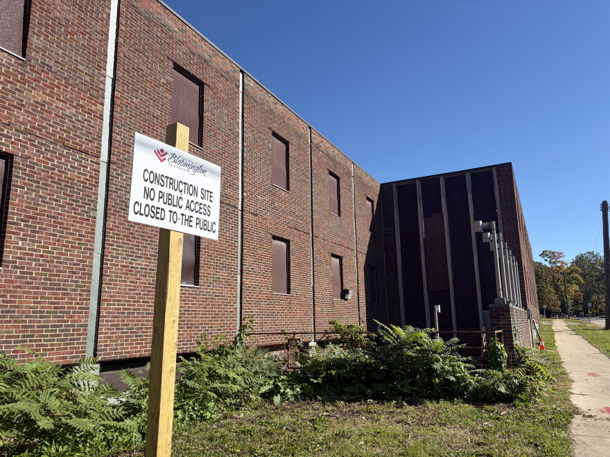 a sign on a wooden post sits in front of a brown brick building