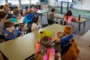 Children sit at tables in a classroom