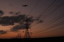 A plane passes over power lines at dusk in San Antonio, Monday, Aug. 3, 2026. (AP Photo/Eric Gay)