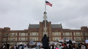 Emmanuel Gutierrez addressed the crowd standing on the school's signage with a megaphone.