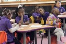 Young girls wearing purple polo shirts work in a classroom