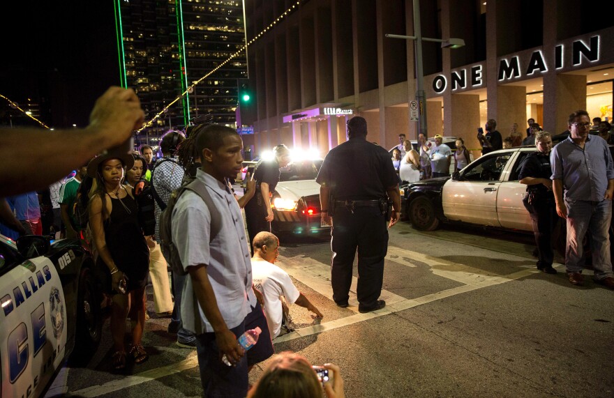 Police attempt to calm the crowd as someone is arrested near the scene of the sniper shooting in Dallas on Thursday.