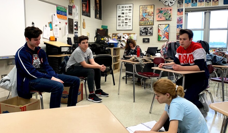 Students sit in classroom and talk. 