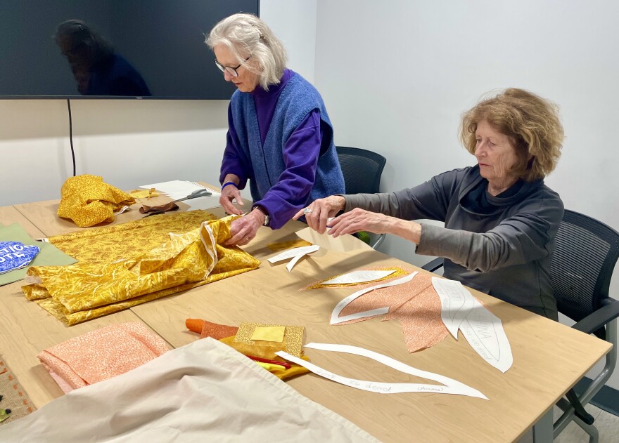 Lois Grady-Wesbecher (left) and Karen Jennings-Laskowski work together to make a quilt segment that depicts recent major wildfires.