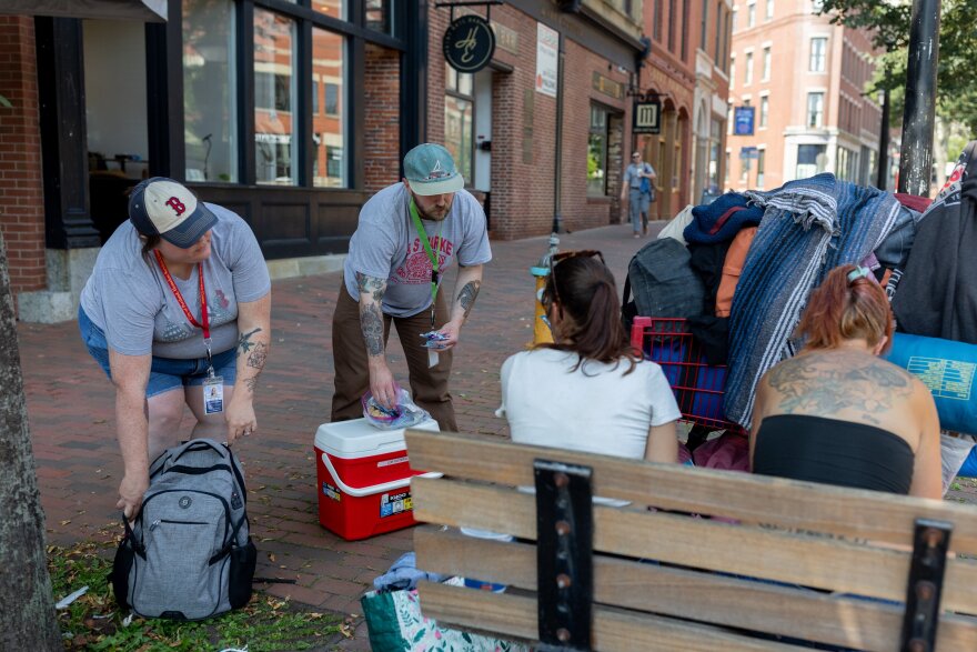 Lauren Chan, left, and Brandon Pratt, hand out water, snacks and electrolyte packs to two homeless women in Portland on July 16. Chan is program coordinator of the city's homelessness prevention and diversion program and Pratt is an outreach team member.