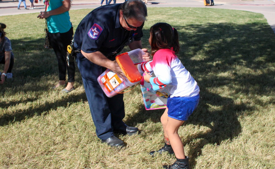 An Abilene firefighter offers Ava Pena a treat outside the zoo.