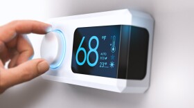 Hand turning a home thermostat knob to set temperature on energy saving mode. fahrenheit units. Composite image between a photography and a 3D background.