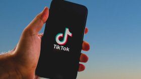 Someone holding a phone with the TikTok logo on the screen.