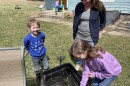 Mom Courtney Tyson looks on as her children dig through a wagon for frog eggs.