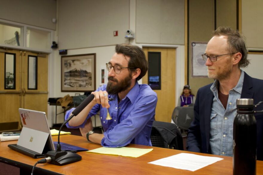 Sopris Sun Editor Raleigh Burley rings a dinner bell while KDNK News Director Morgan Neely looks on at the Carbondale Board of Trustees Candidate Forum on March 16, 2022
