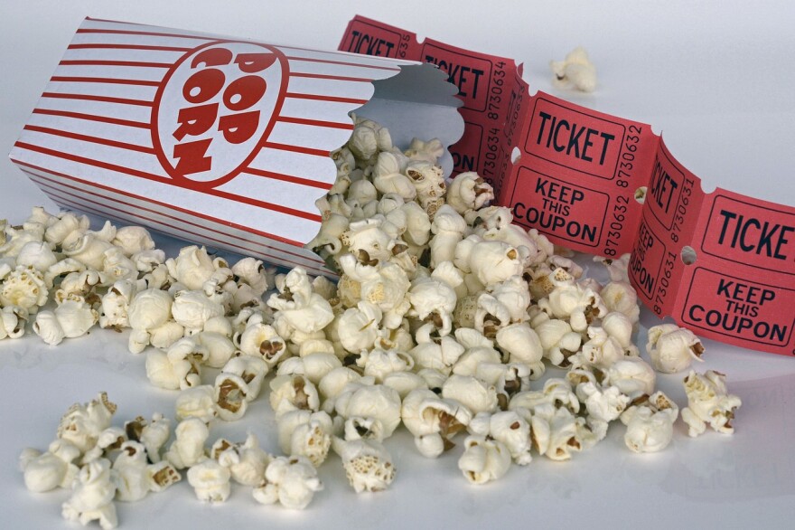 Popcorn spilling out of a container next to movie ticket stubs