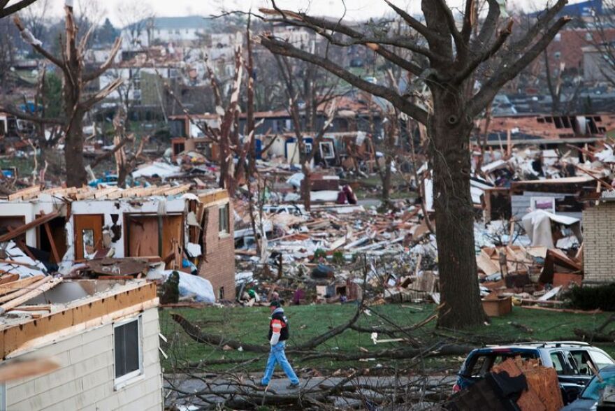 In this Nov. 18, 2013, file photo, a man walks through what is left of a neighborhood in Washington, Ill., a day after a tornado ripped through the central Illinois town.