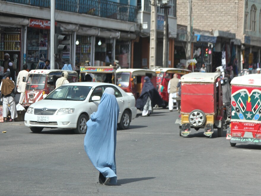 A woman crosses the street in Herat, Afghanistan. Burqa-clad women stand out on the streets in Afghanistan â both because of their bright blue burqas, and because there are far fewer women in public than men.