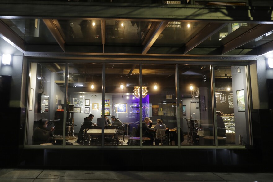 Customers sit in a dining area of Cafe Cosmos in downtown Seattle, Sunday, March 15, 2020. Gov. Jay Inslee said Suday night that he would order all bars, restaurants, entertainment and recreation facilities closed for 2 weeks.