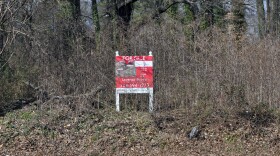 Sign on overgrown lot saying sold