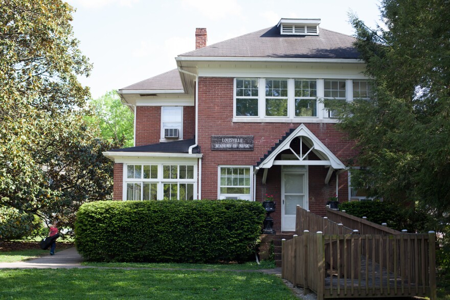 Brick house surrounded by shrubbery, a large magnolia tree and a wheelchair accessible ramp 