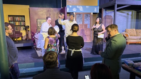 People standing on a stage wearing 1950s period costumes.