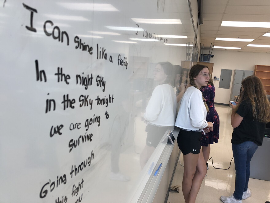 Stoneman Douglas students participating in a songwriting workshop offered after a session of Camp Shine write their lyrics on a whiteboard in a classroom at Westglades Middle School. The lyrics reflect their suffering after the shooting at their school.