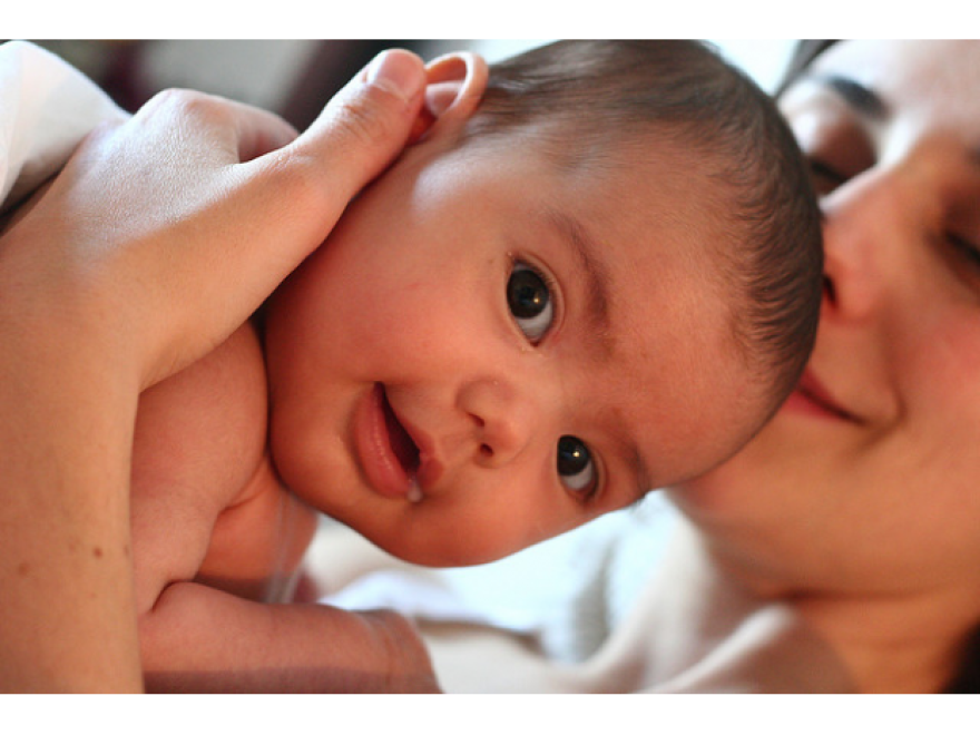 A picture of a baby held by a mother.