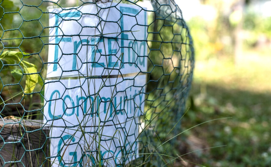 A sign reading "Free Food Community Garden" welcomes visitors to the garden.