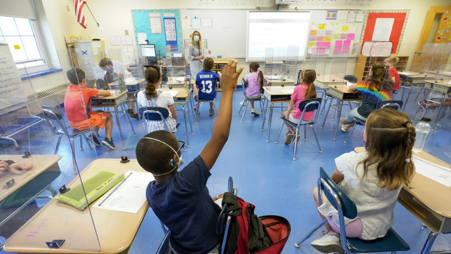 FILE - In this May 18, 2021, file photo, a teacher, center, and her third grade students wear face masks and are seated at proper social distancing spacing during as she conducts her class in Rye, N.Y. In response to a push for culturally responsive teaching that gained steam following last year's police killing of George Floyd, Republican lawmakers and governors have championed legislation to limit the teaching of material that explores how race and racism influence American politics, culture and law. The measures have become law in Tennessee, Idaho and Oklahoma and bills have been introduced in over a dozen other states. (AP Photo/Mary Altaffer, File)