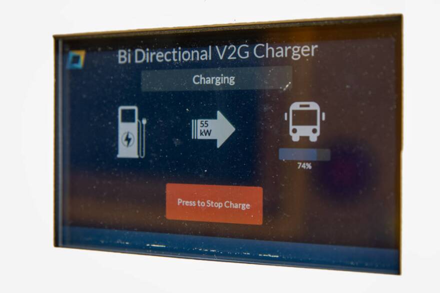 The front panel of an electric school bus charging station shows the direction of charge, as well as power and battery level. (Robin Lubbock/WBUR)