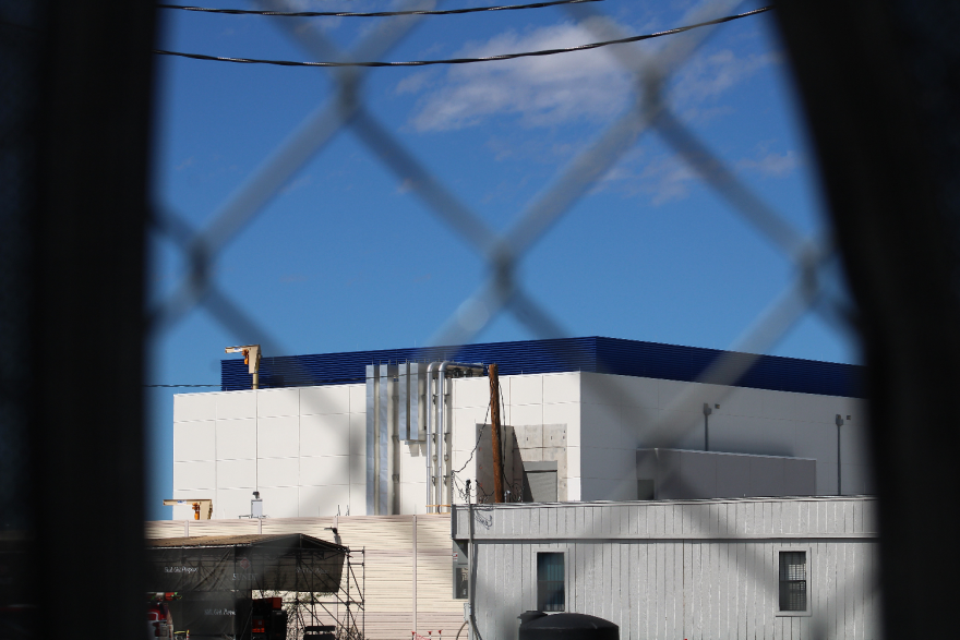 An industrial building, as photographed through a chain link fence.