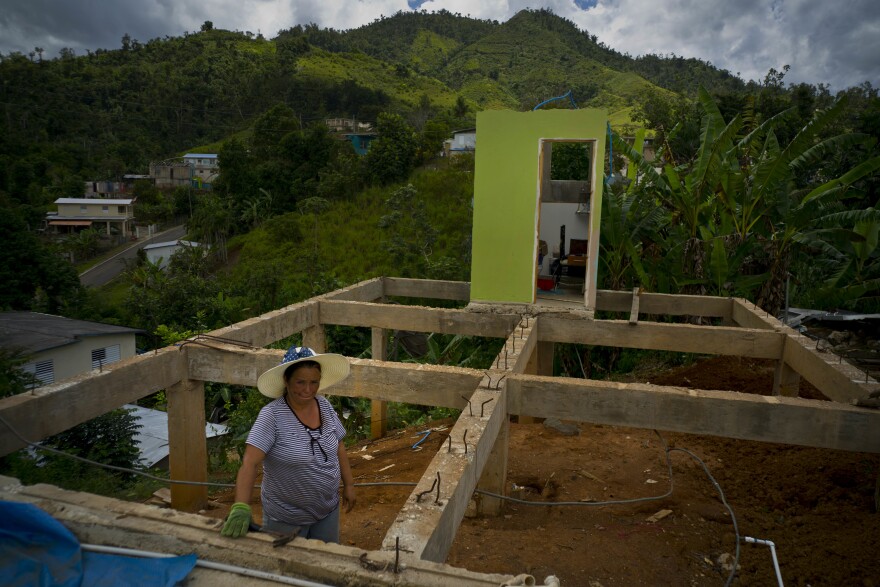 In this Sept. 8, 2018 photo, Alma Morales Rosario poses for a portrait between the beams of her home being rebuilt after it was destroyed by Hurricane Maria one year ago in the San Lorenzo neighborhood of Morovis, Puerto Rico.