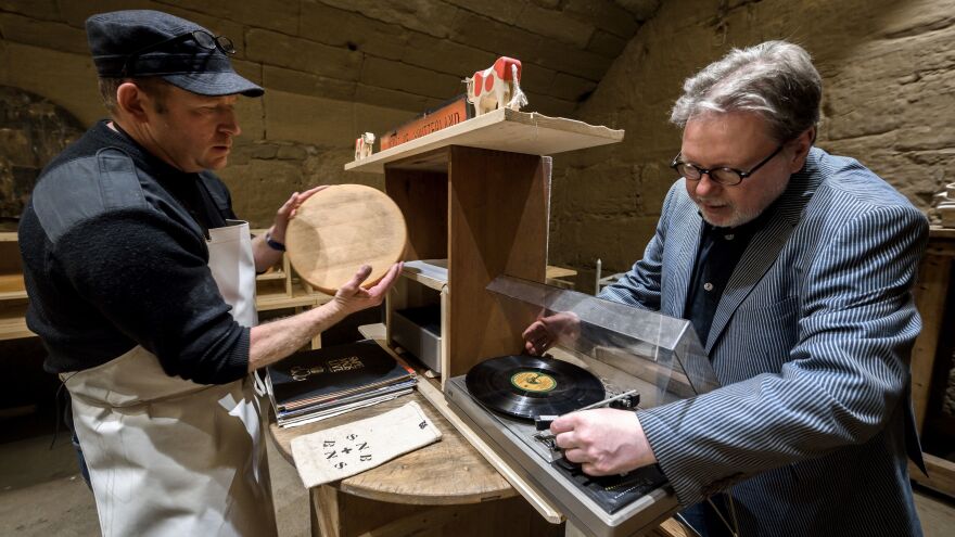 Swiss cheesemaker Beat Wampfler (left) and Michael Harenberg, director of the music department at the Bern University of the Arts, pose with a vinyl record and a wheel of Emmental.
