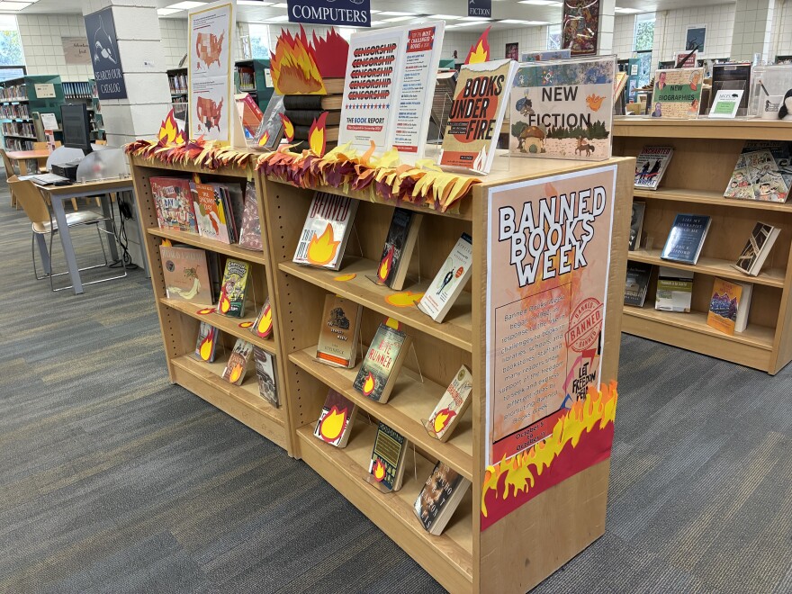 photo shows a library shelf displaying books that have been banned in other places.