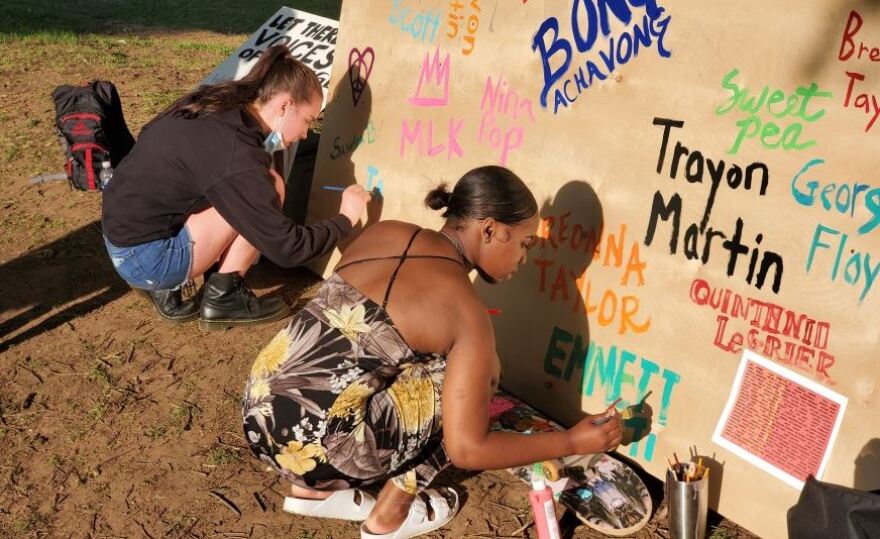 Iamoni McClellan, right, paints the name of Emmett Till on a board remembering the victims of racist violence. Photo was taken June 5, 2020, in Freedom Park.