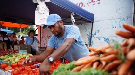 Miguel Quiroz arranges tomatoes at ASIA's Hapi Fresh Market in Akron's North Hill neighborhood on July 31, 2024.