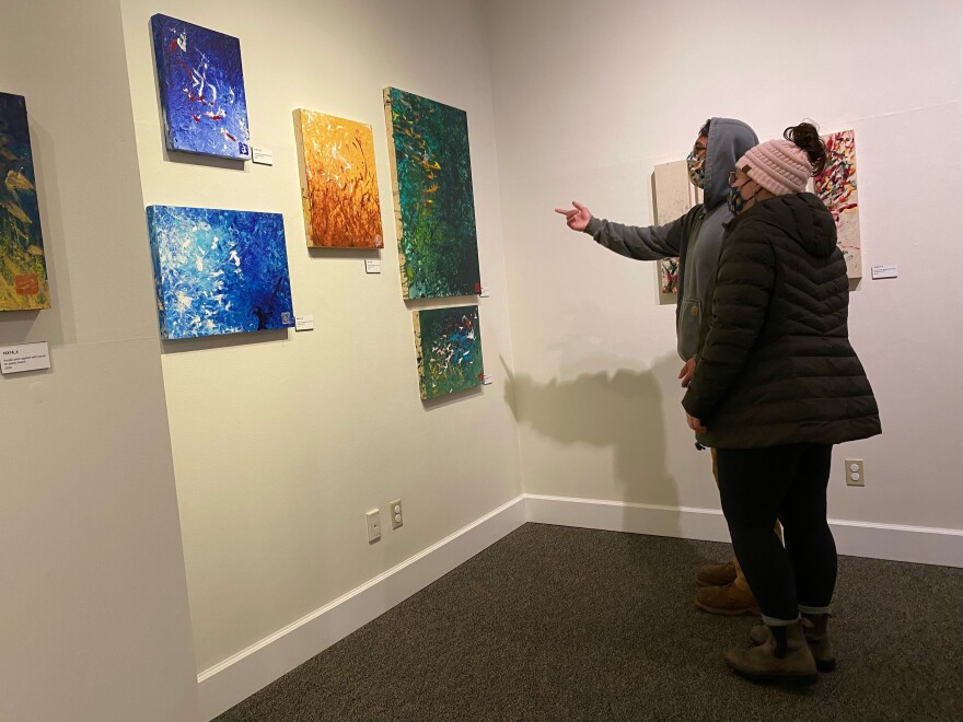 People look at art on the wall.
