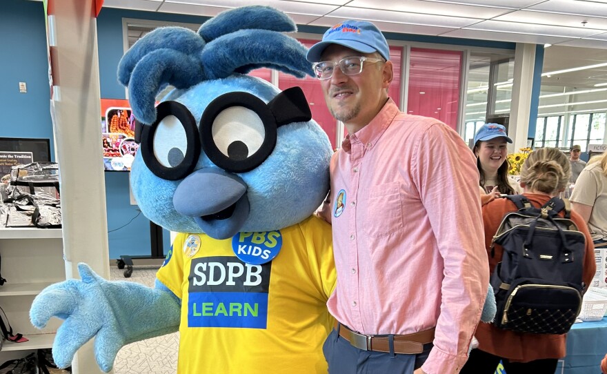 The mayor of Aberdeen is posing for a picture with Buddy the Bird from SDPB. 