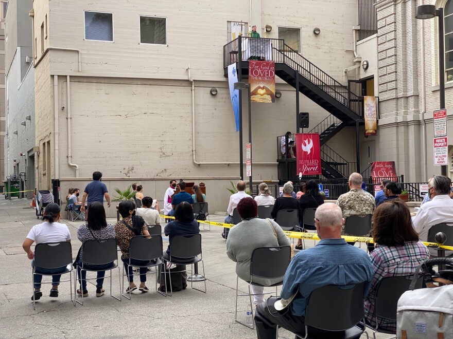 Father Michael O'Reilly preaches from a third-floor fire escape in a Sacramento alley while indoor worship services are prohibited due to COVID-19 heath restrictions.