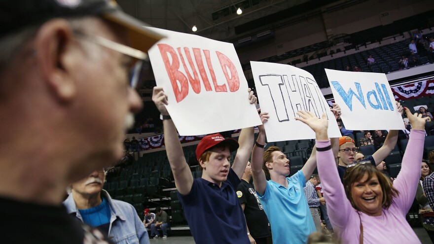 People hold signs that read "Build That Wall" ahead of a Trump campaign rally on Feb. 12, 2016, in Tampa, Fla.