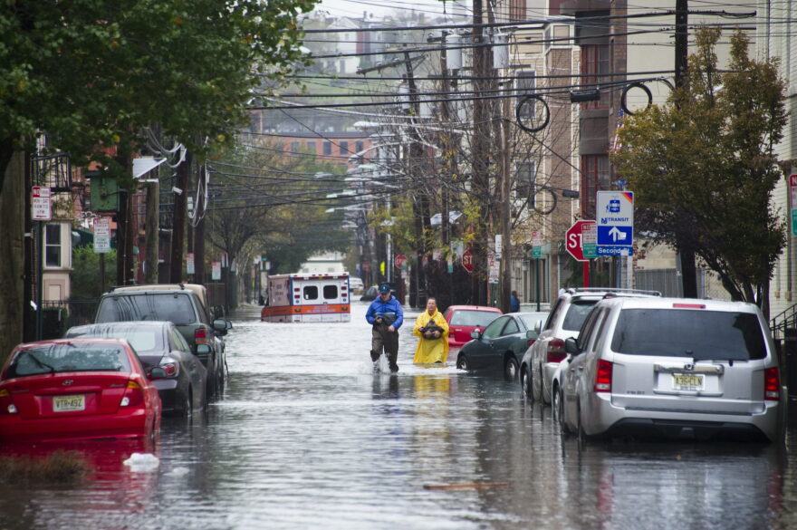 Residents walk through flood water and past a stalled ambulance in the  aftermath of Superstorm Sandy on Tuesday, Oct. 30, 2012 in Hoboken, NJ. (Charles Sykes/AP)
