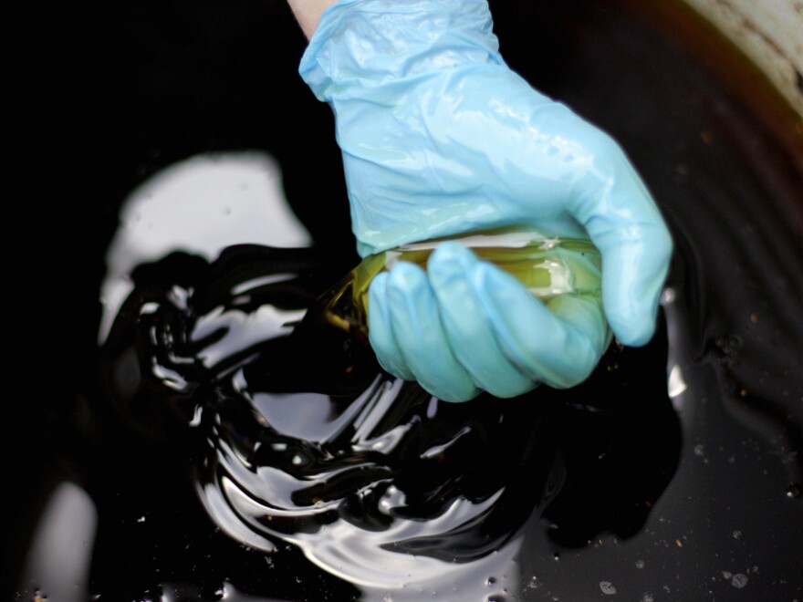 A worker with cooking oil in a holding barrel behind an Ashton, Maryland restaurant. 