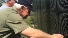 Two Vietnam Soldiers look at moving wall to find names of friends lost in the war.