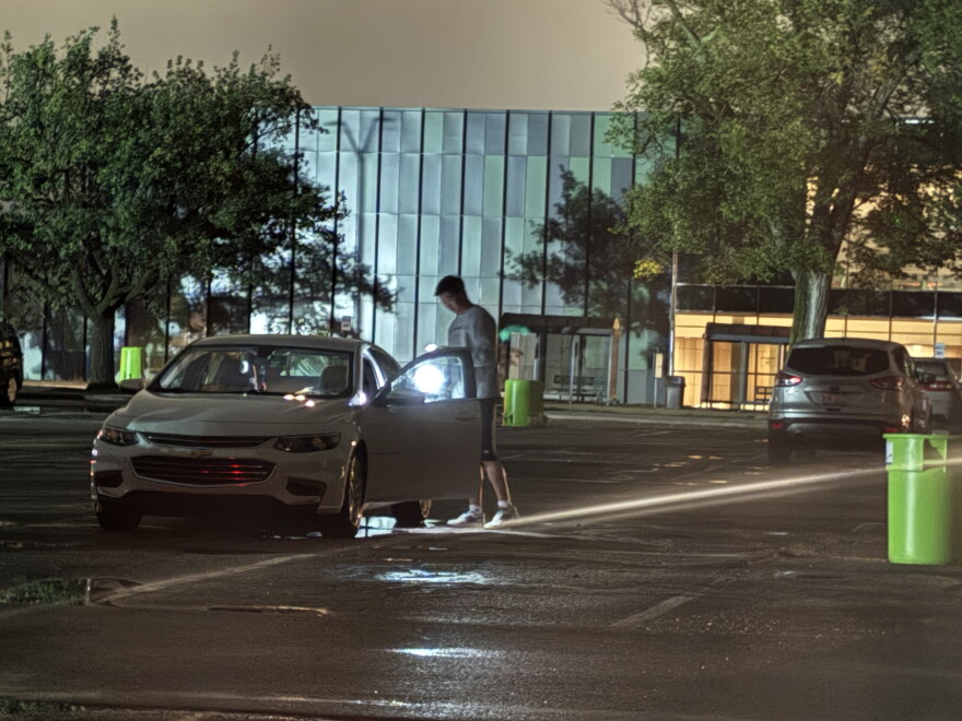 A person uses a flashlight near a vehicle on Michigan State University’s East Lansing campus during a widespread power outage Saturday night, Sept. 19, 2026.